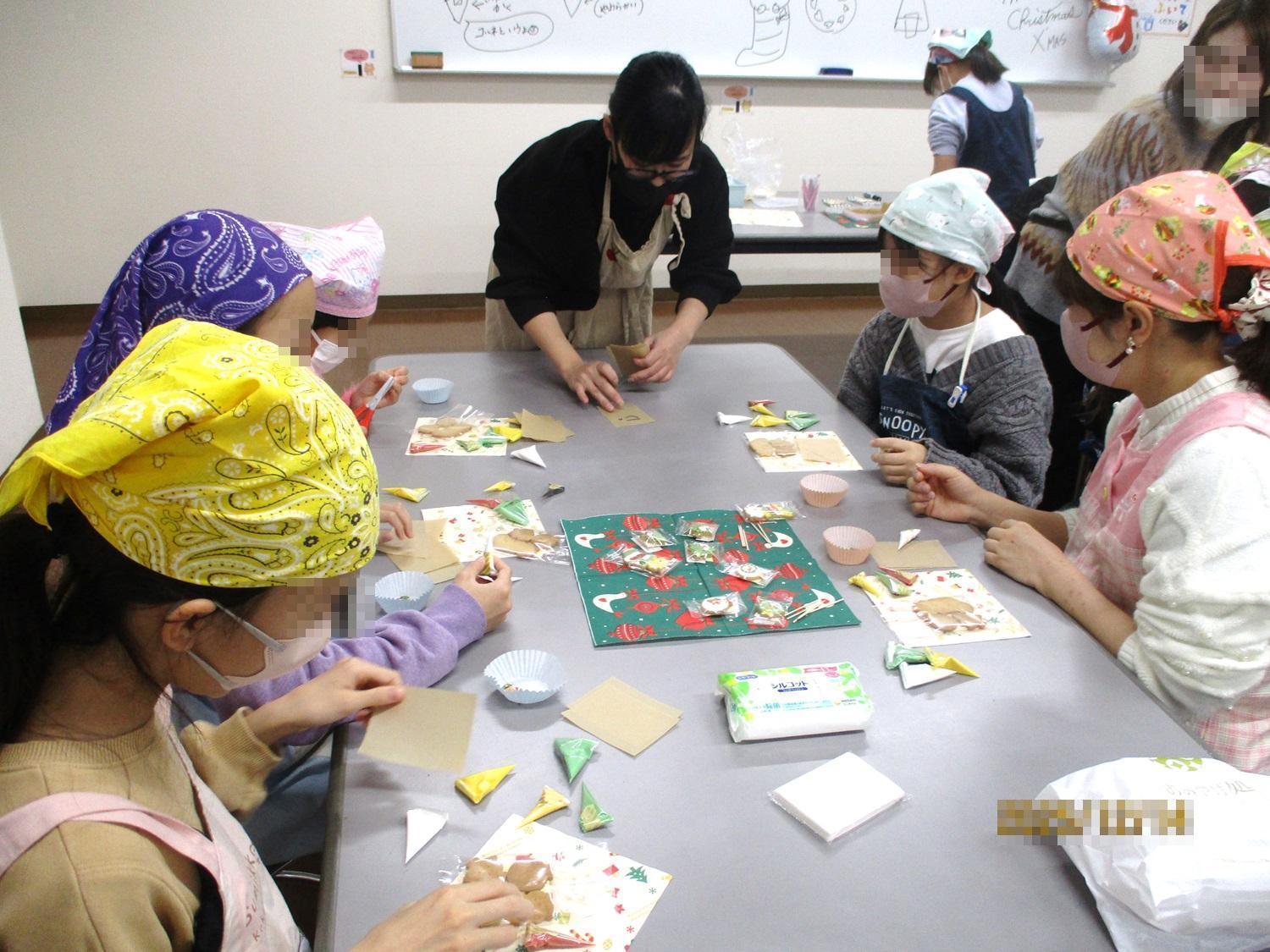 アイシングクッキーの作り方の説明をする講師とそれを聞いている生徒たち