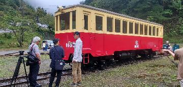 建屋から出たキハ3の前でカメラマンに説明する、なつかしの尾小屋鉄道を守る会会長