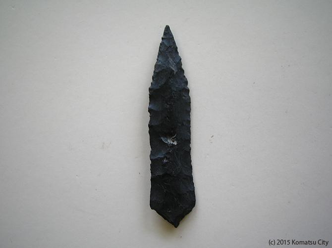 黒色でひし形、上が細長く下が短く先端が尖っている打製石鏃 通番号:641の写真