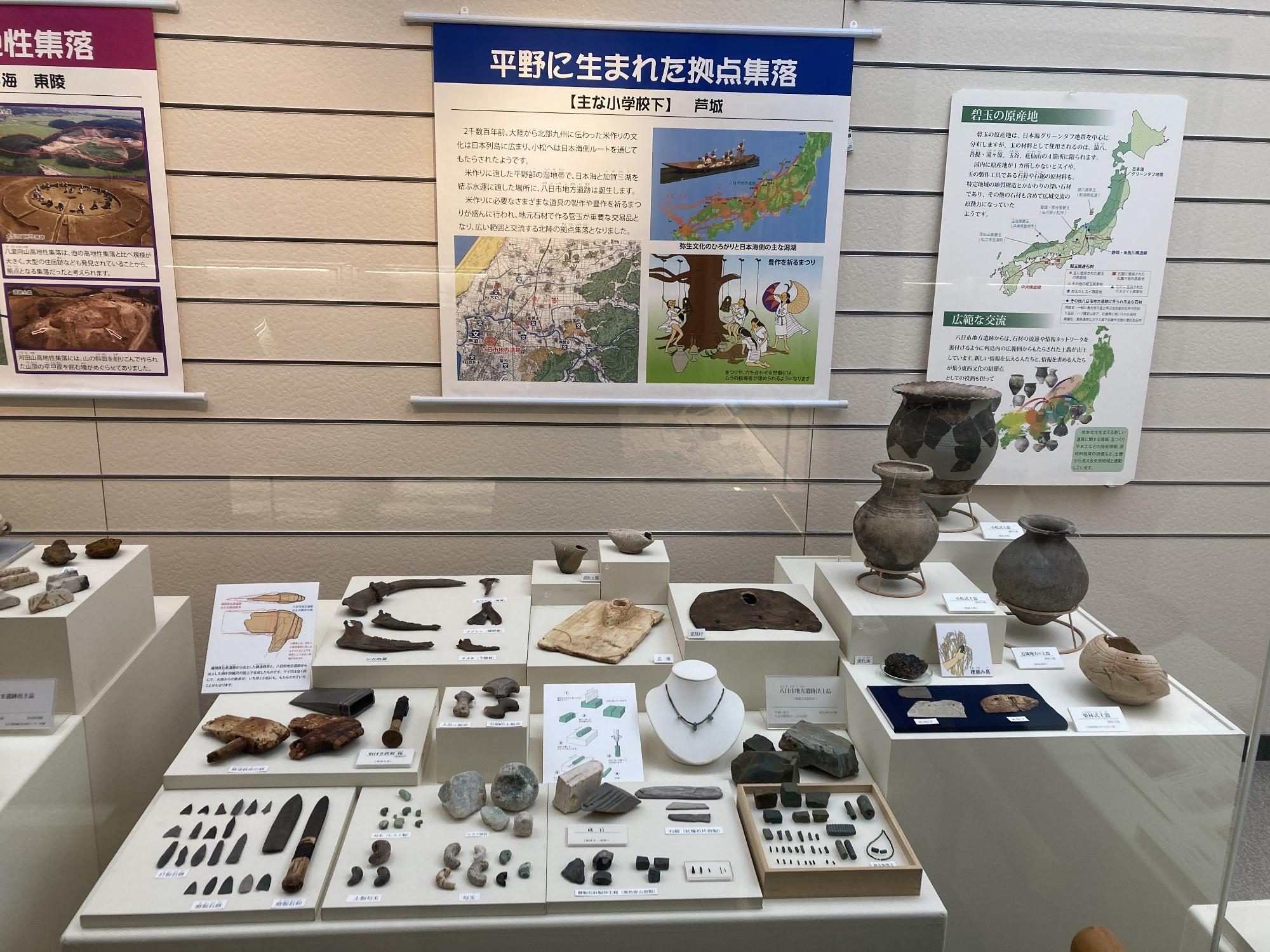 たくさんの石器や土器、装飾品などが展示された「平野に生まれた拠点集落」の展示スペースの写真