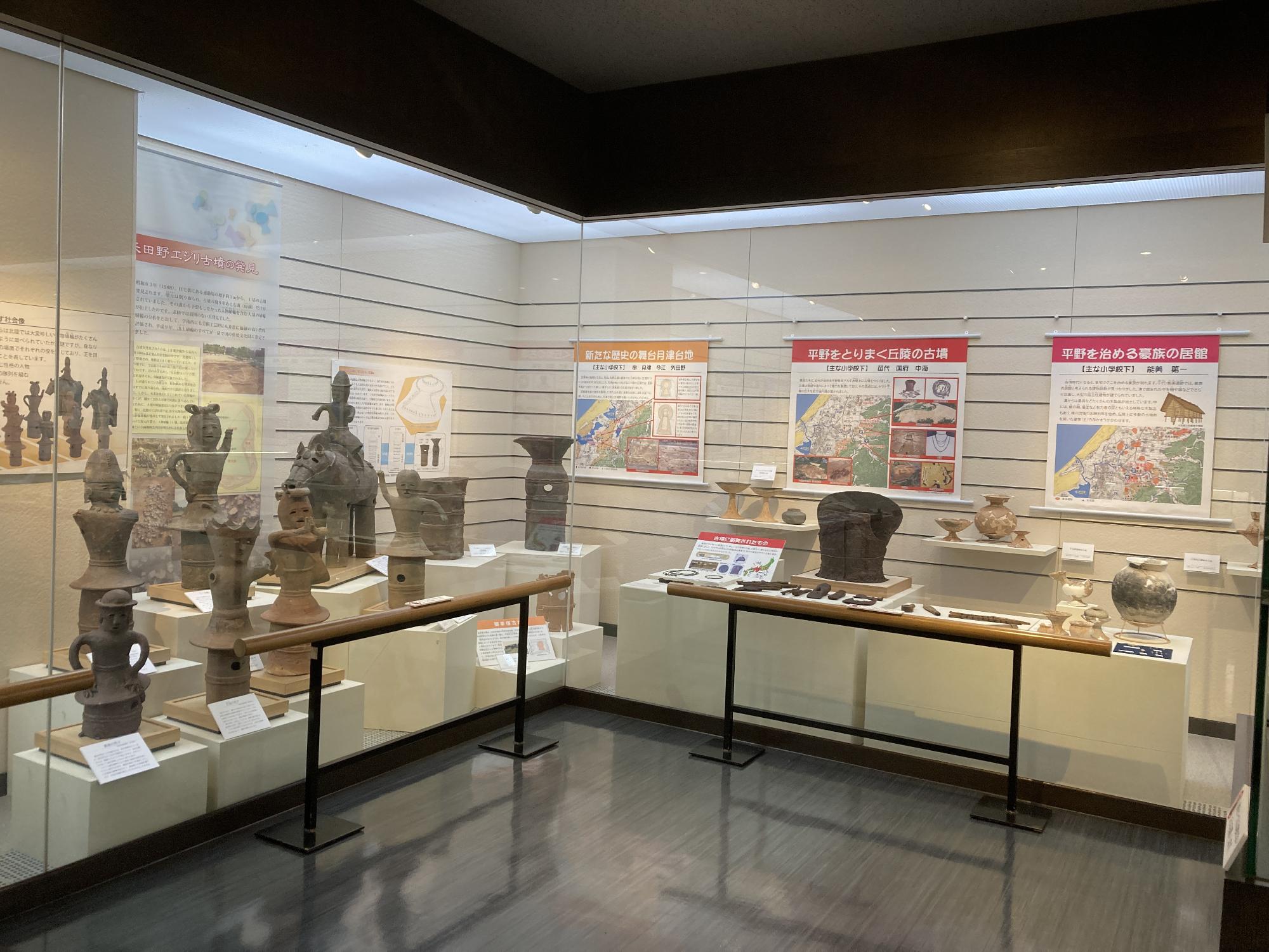 壁の展示ケースに出土されたたくさんの埴輪や土器が展示されている写真