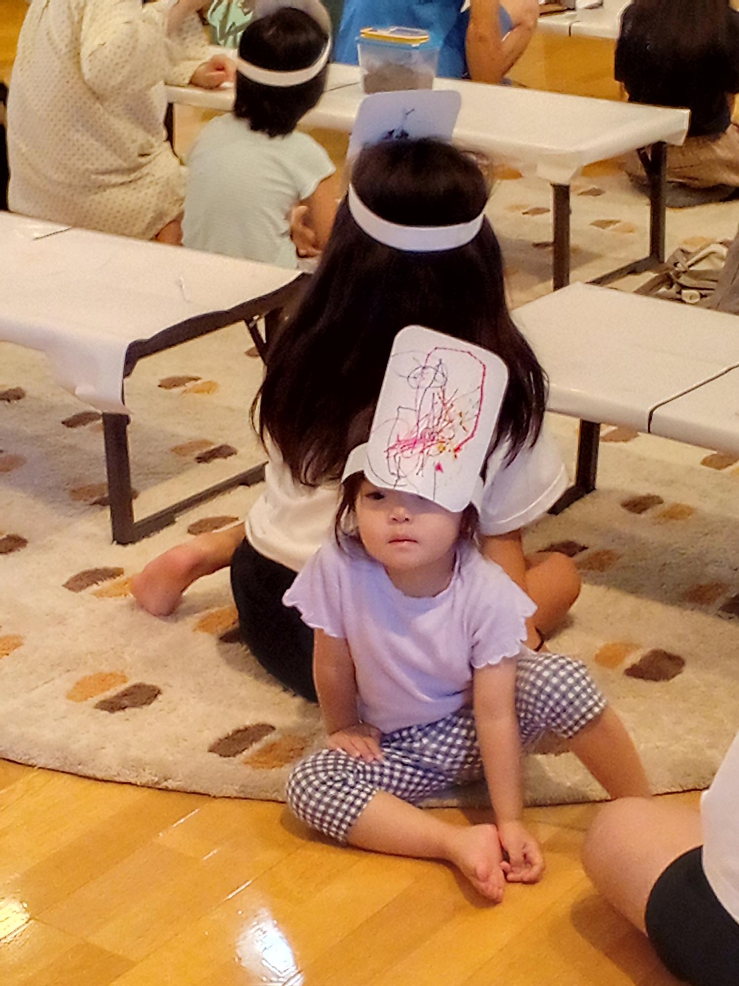 描いた絵をお面にしてあたまにつけている子どもの写真