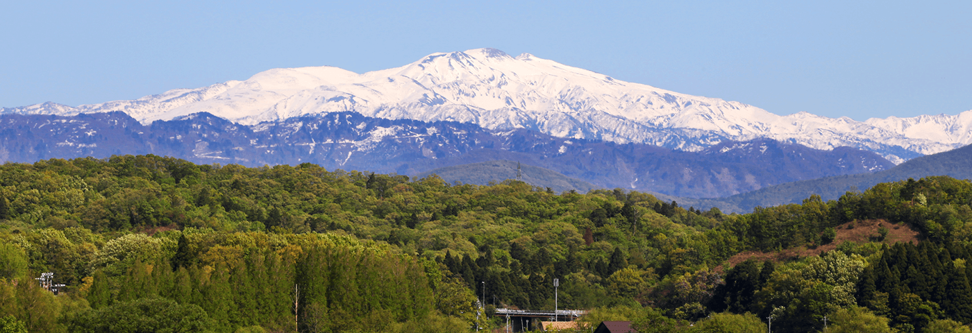 木場潟から望む霊峰白山の写真（雪化粧をした霊峰白山の手前に木々に囲まれた小屋がありその手前に湖がある）