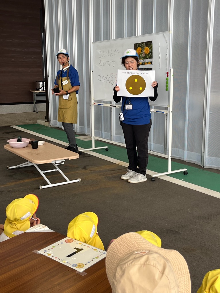 土に穴をあける指導をする古橋さん