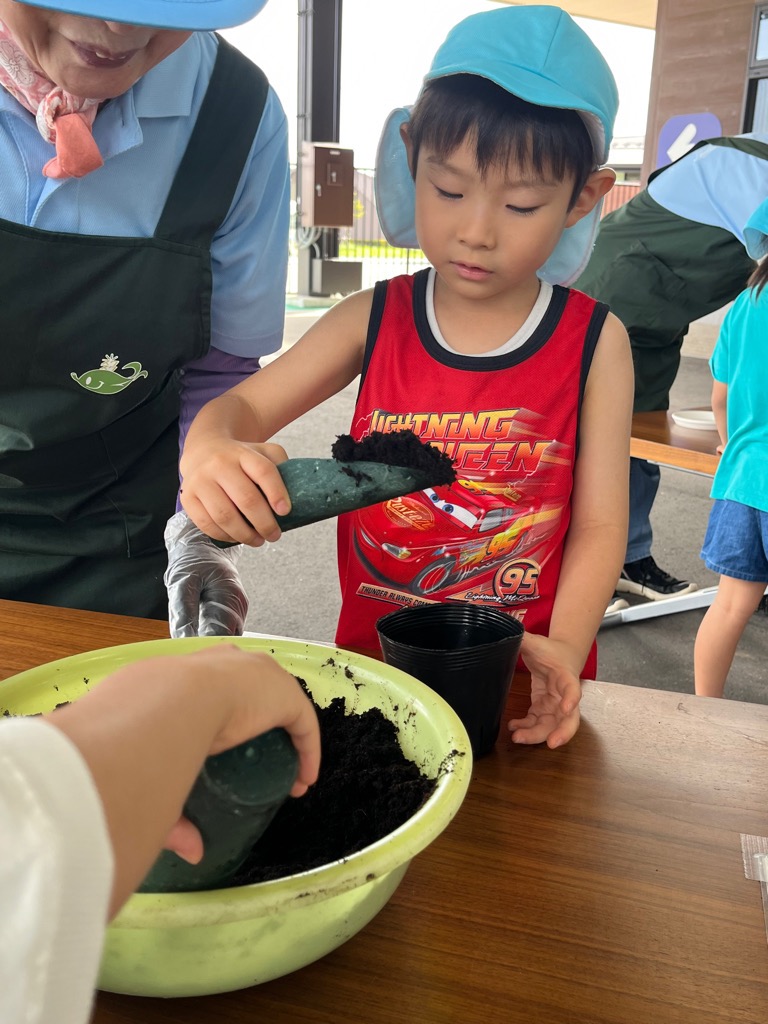 ポットに土を入れる園児