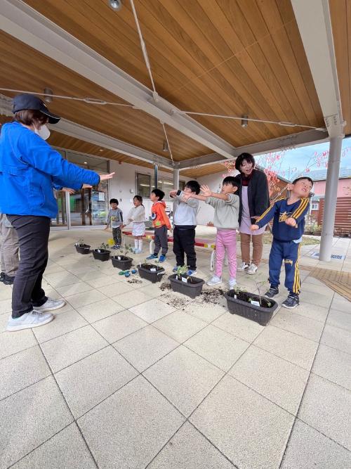 おまじないを苗にかける園児