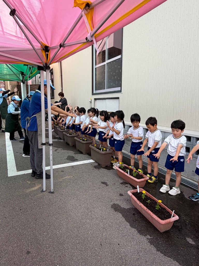 植えた苗におまじないをかける園児