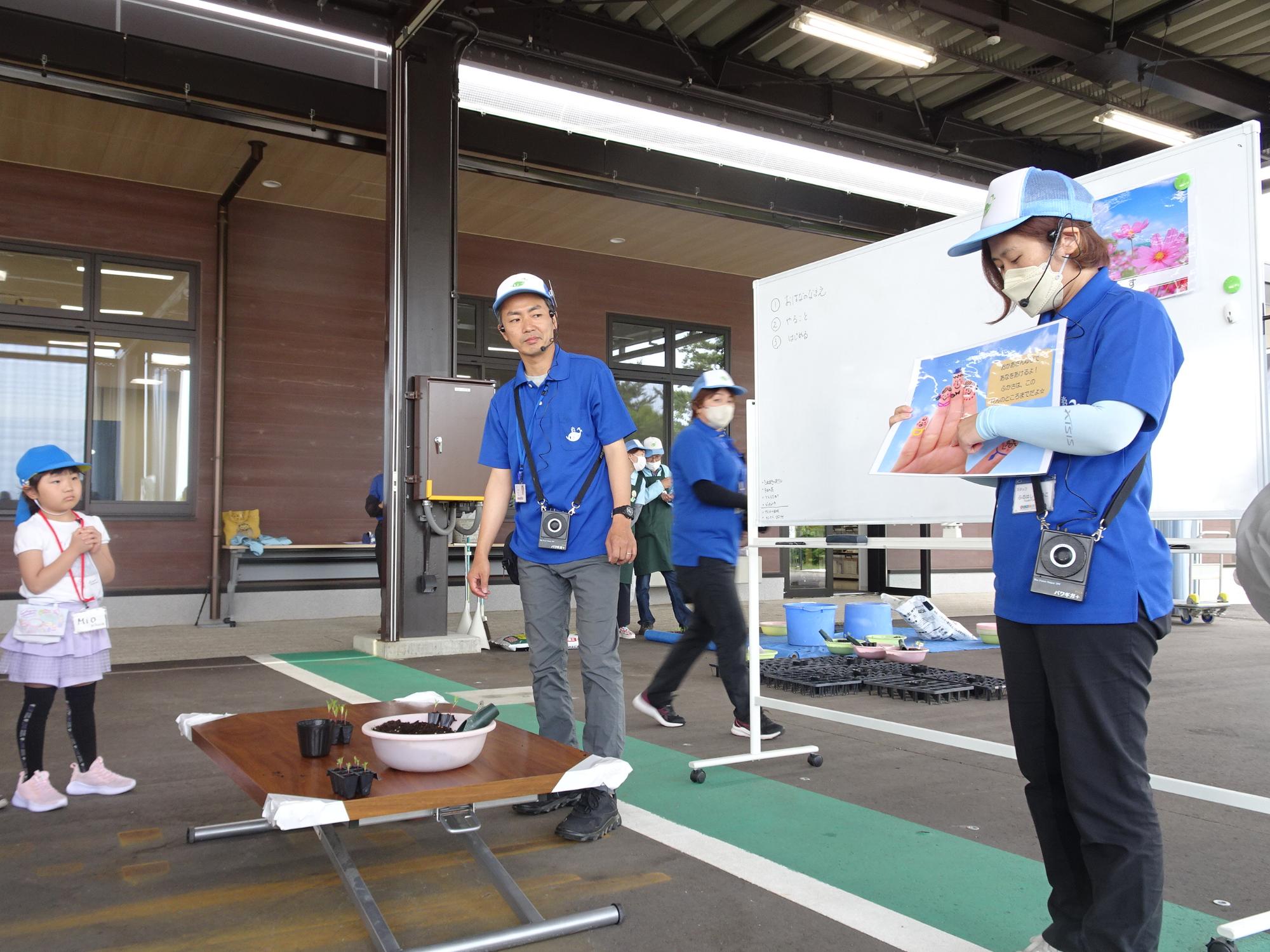 スタッフの女性が用紙を持ちながら説明をしている写真