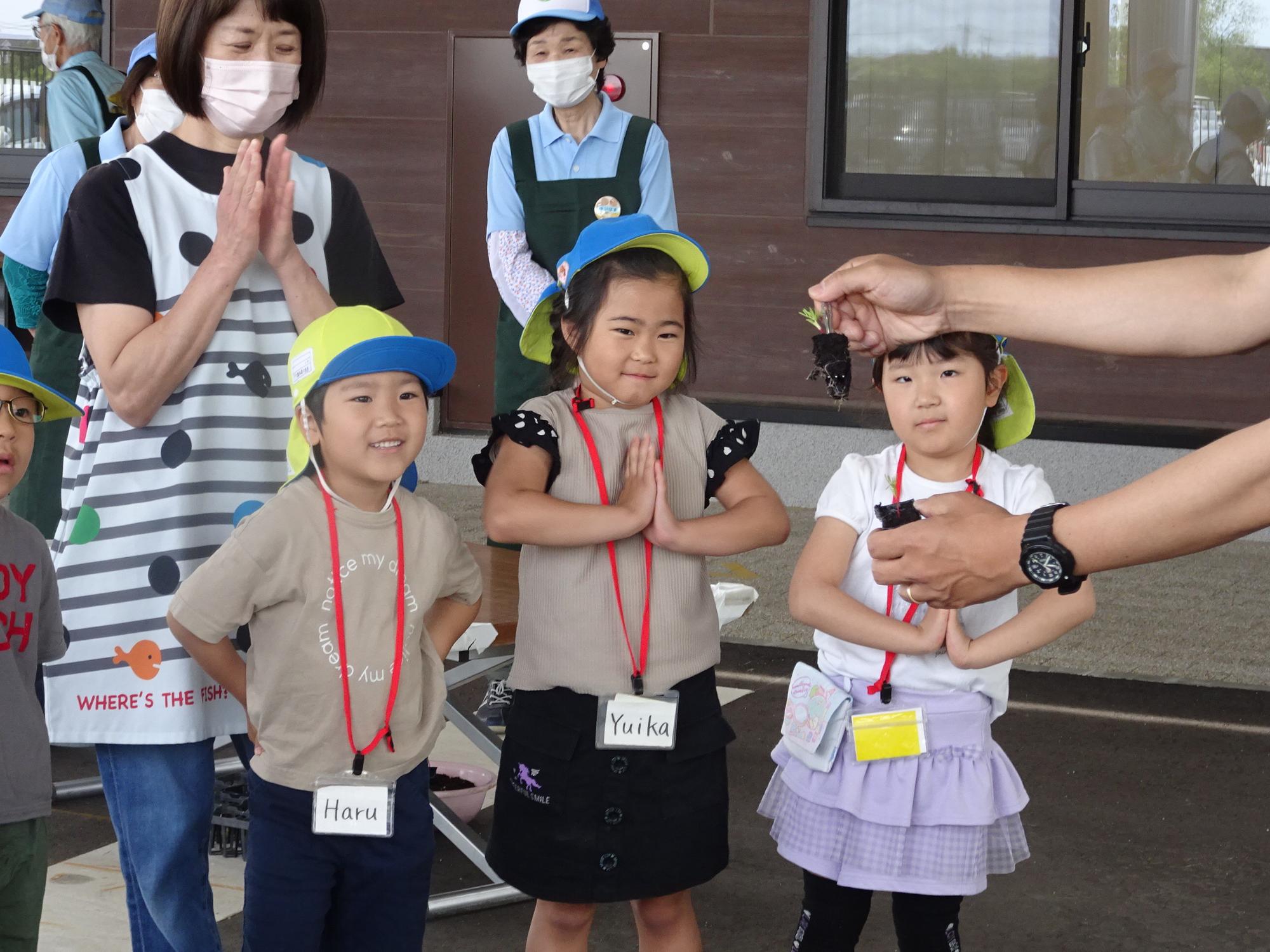 園児3名の前で抜けた苗を手に取り説明をしている写真