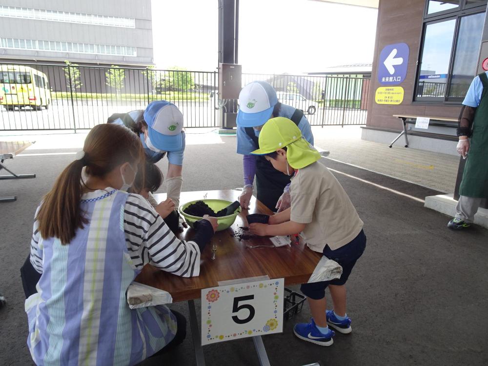 「5」と書かれた紙が貼られた机の周りで作業をしている園児とスタッフの人達の写真