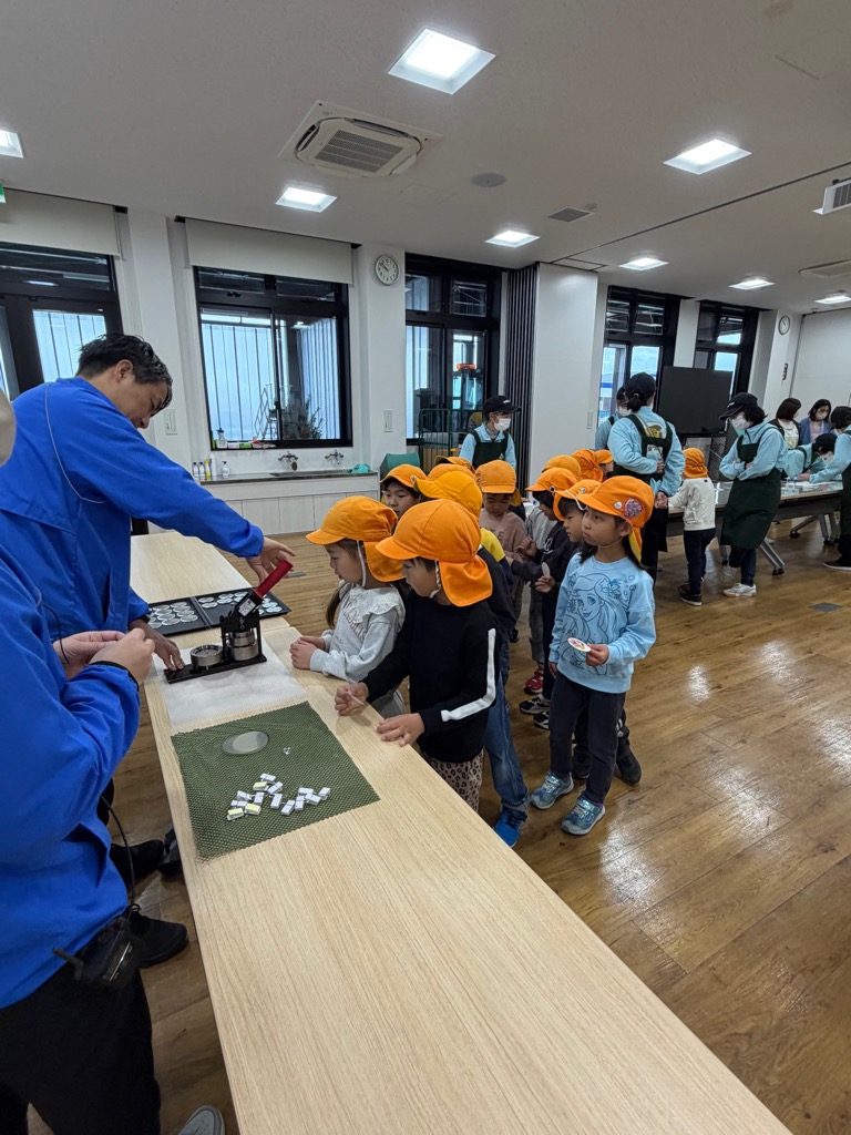 押し花の台紙を缶バッチにしてもらう園児たち
