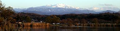 湖の後ろにそびえる頂上に雪をかぶった白山を木場湖畔公園から写した風景写真