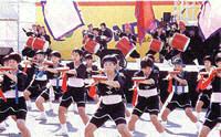 奥にあるステージ上では太鼓を持って演奏し、手前にはたくさんの子供たちが並んで踊りを披露している様子の写真