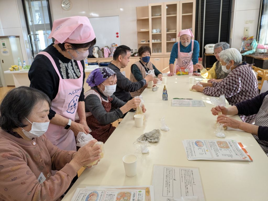 参加者の方がポリ袋に入れたバナナをつぶしているいるのを食改さんが見守っている写真