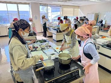 三角巾とエプロンを付けた参加者の方々がグループに分かれて調理台でt調理をしている様子の写真