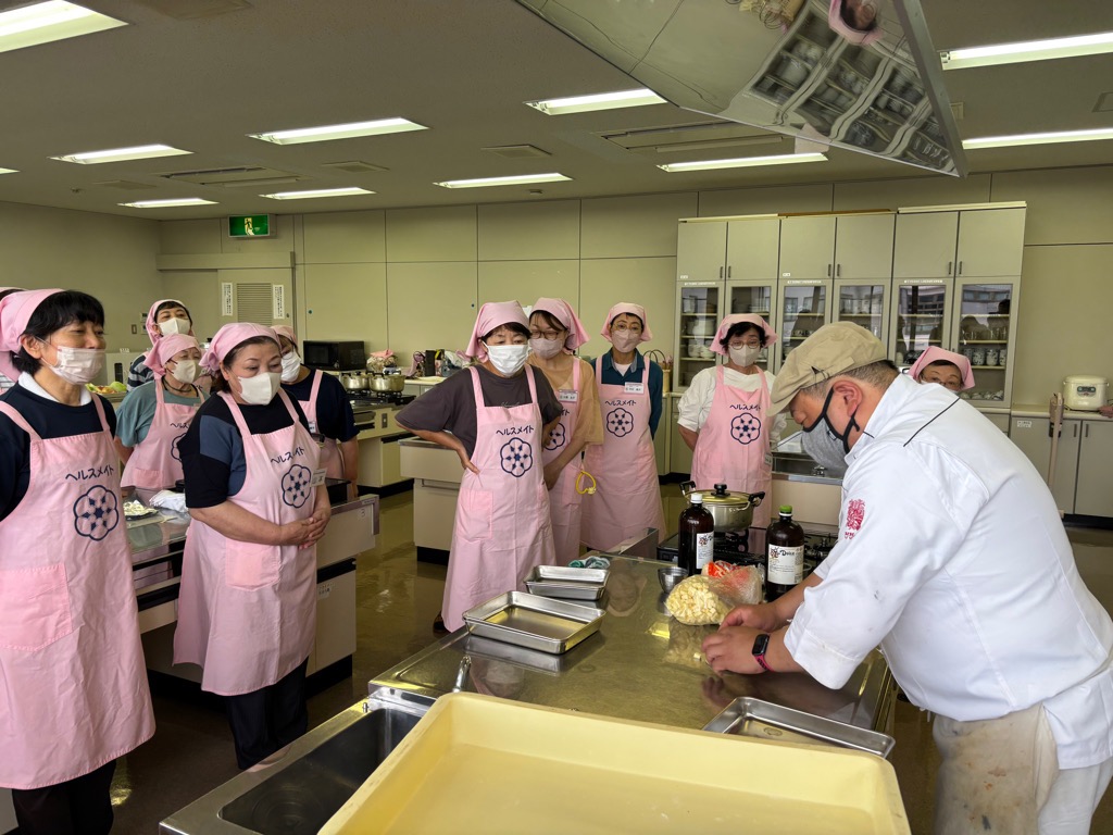 食改さんが講師よりパン生地の広げ方を教わっている写真