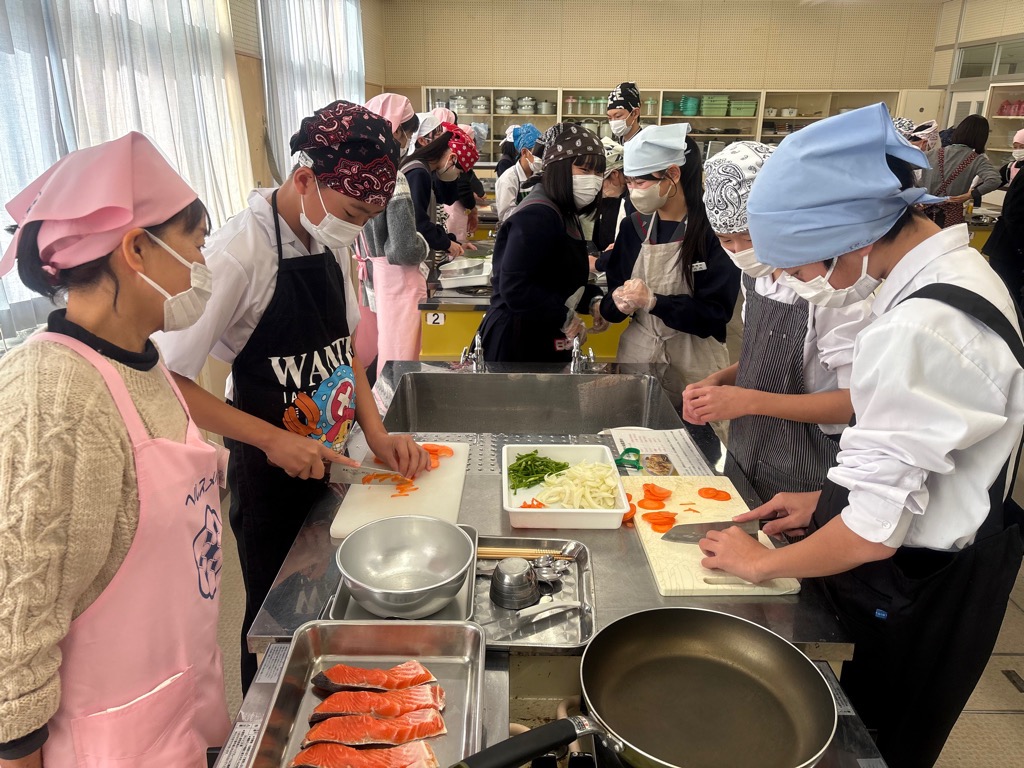 中学生が野菜を切るのを見守る食改さんの写真