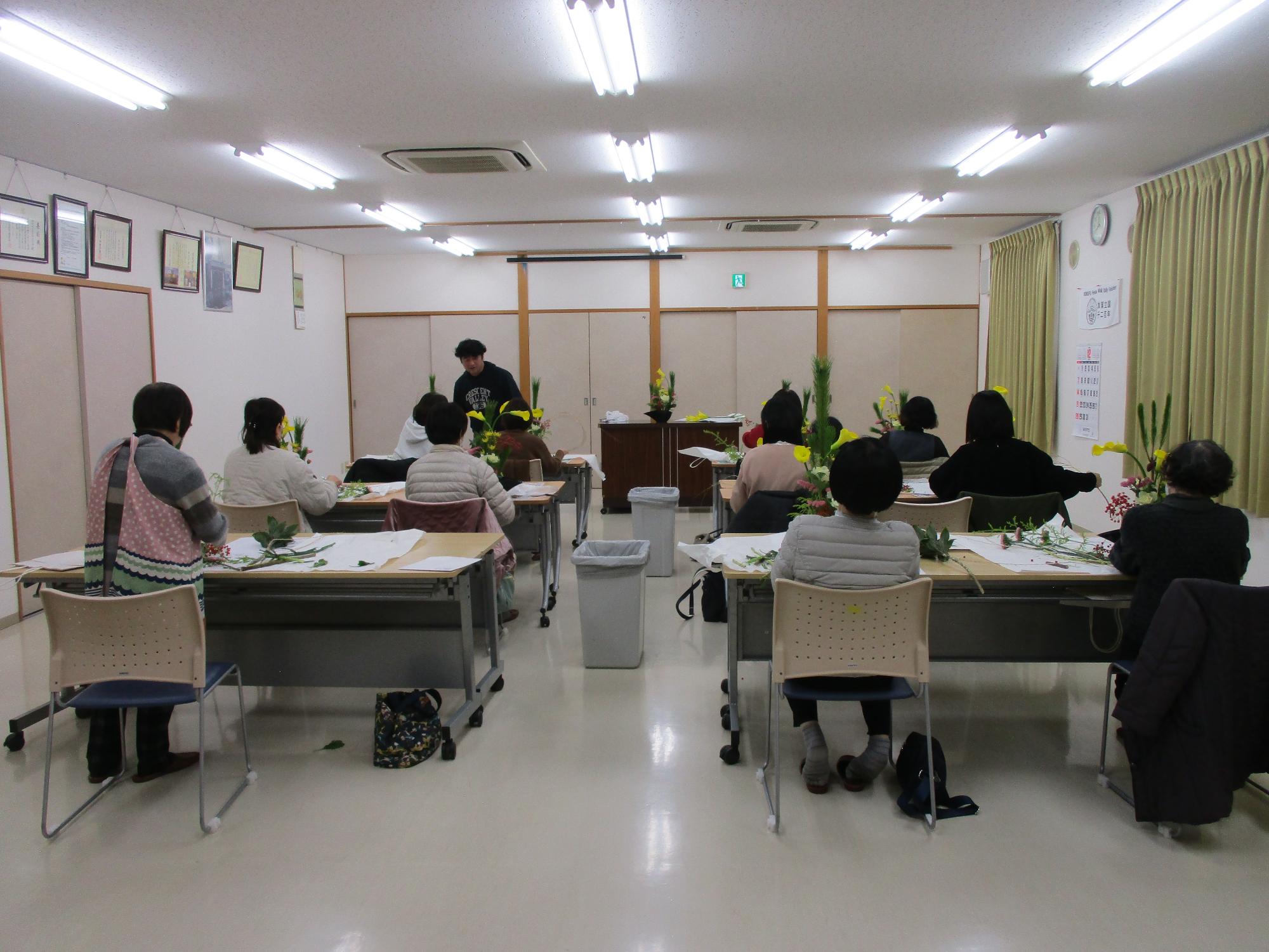 講師の指導を受けながらお正月花フラワーアレンジメントを作る受講生の写真