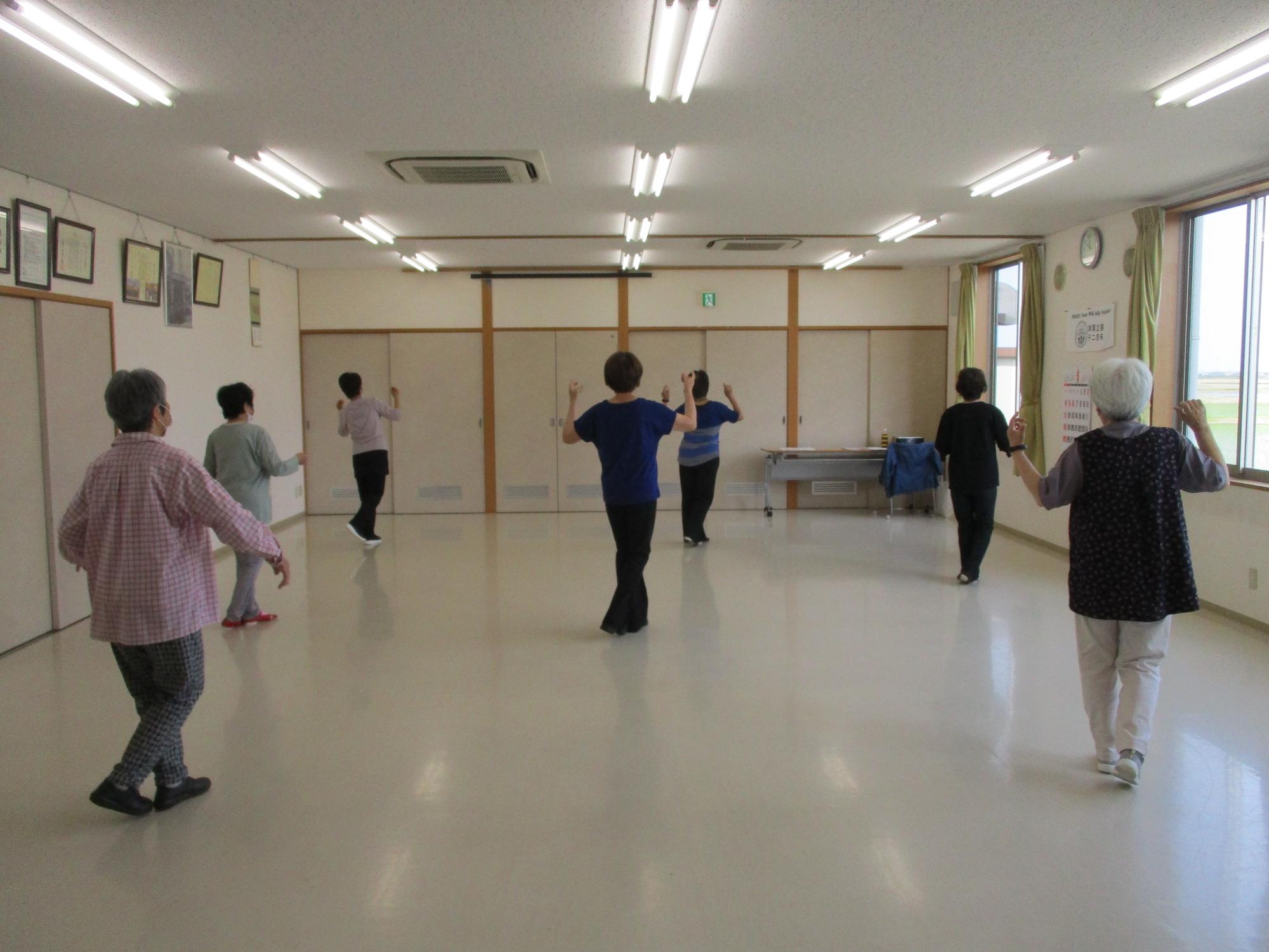 音楽にあわせて両腕をあげ足をクロスしてダンスをしている写真