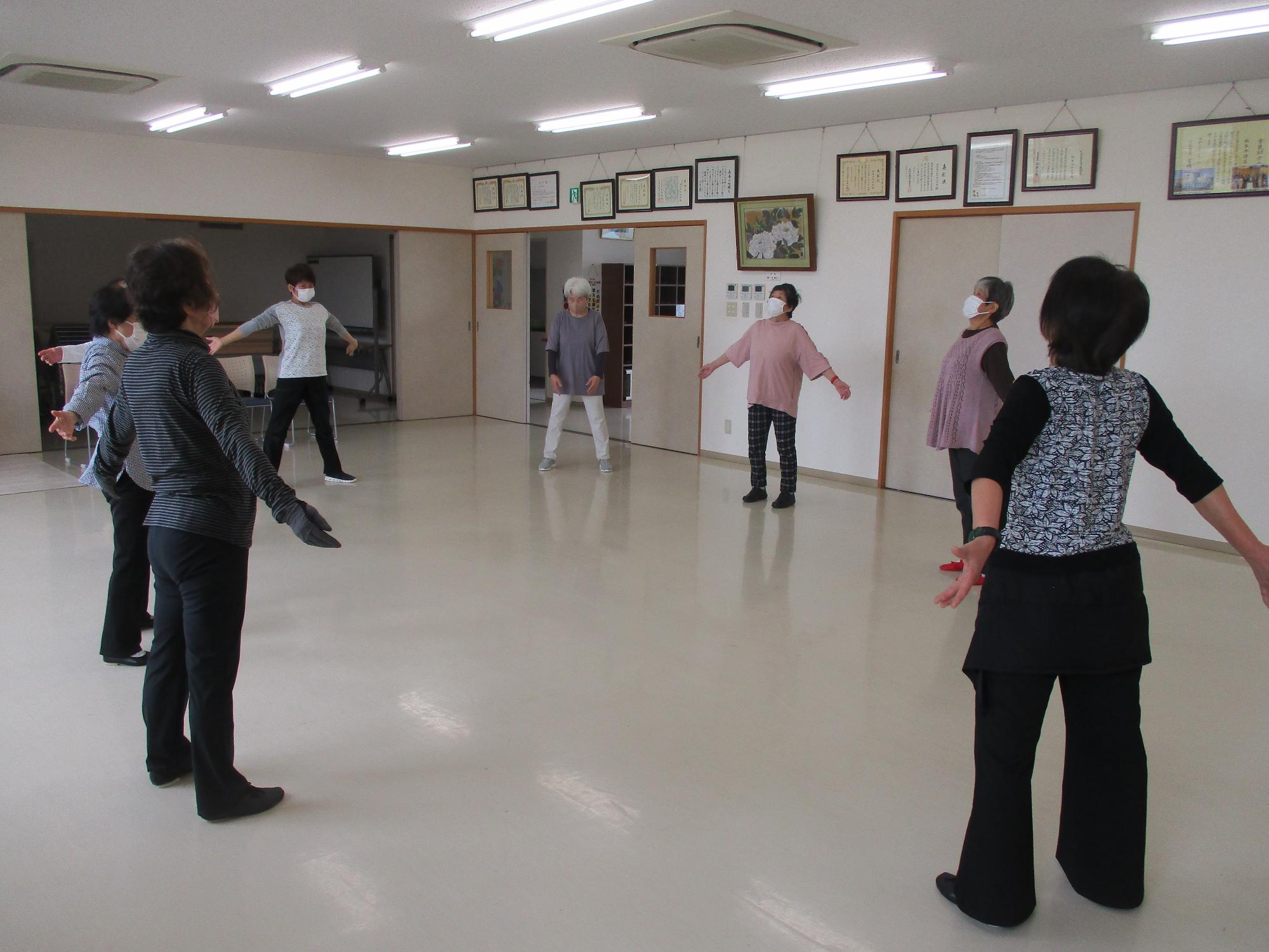 輪になり両腕を広げ深呼吸をしている写真