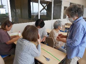 受講生が講師を囲み作品制作に見入る様子