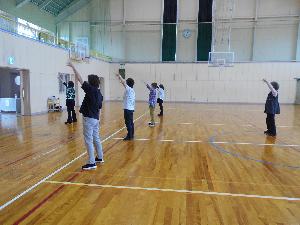 体育館の中で5名の女性が左手を上げながらリズムダンスする様子