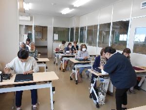 研修室の中で受講生に書道の指導をしてまわる講師の様子