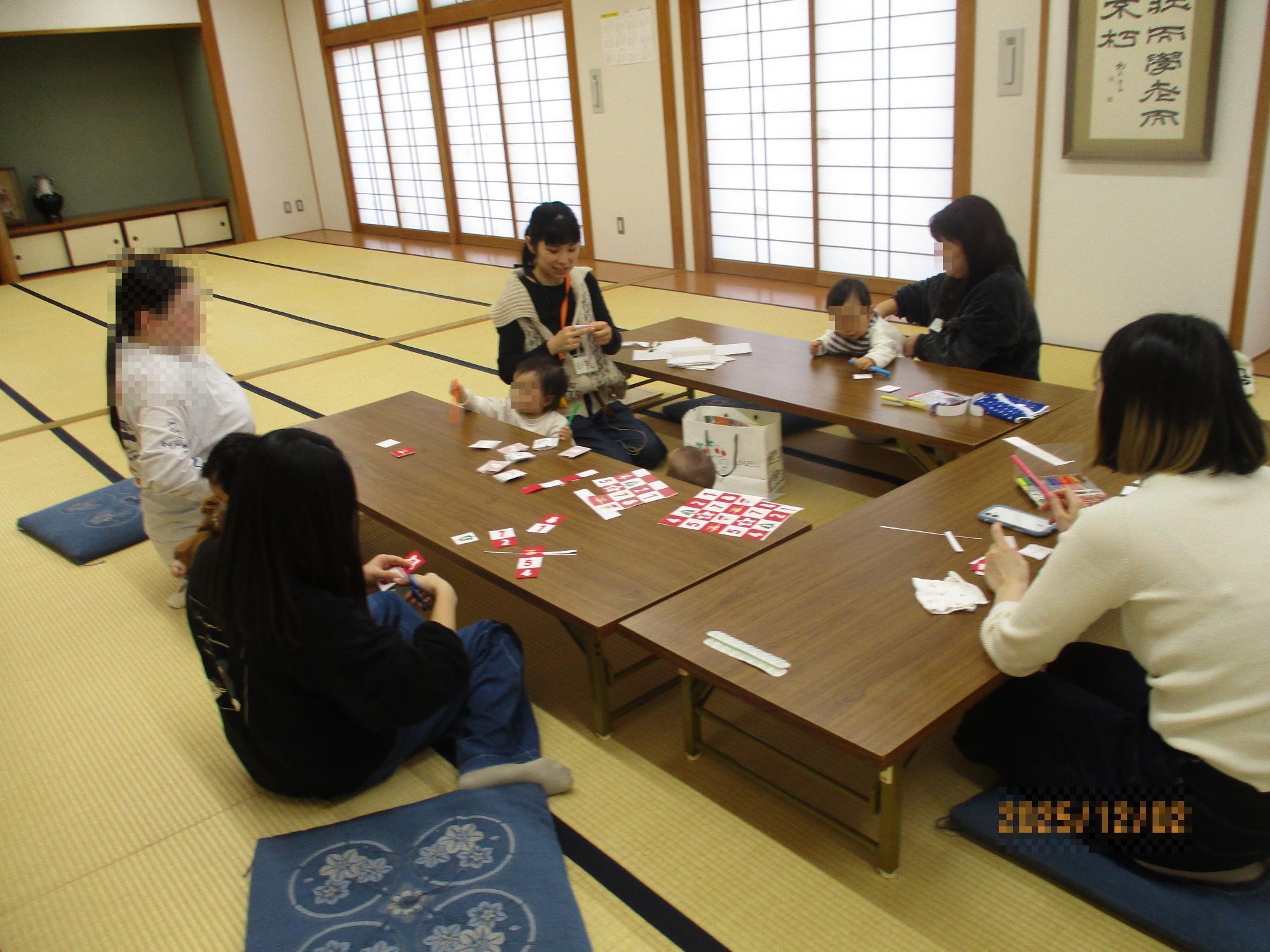 テーブルで手づくりのアドベントカレンダーづくりをするママとそれを見ているベビー