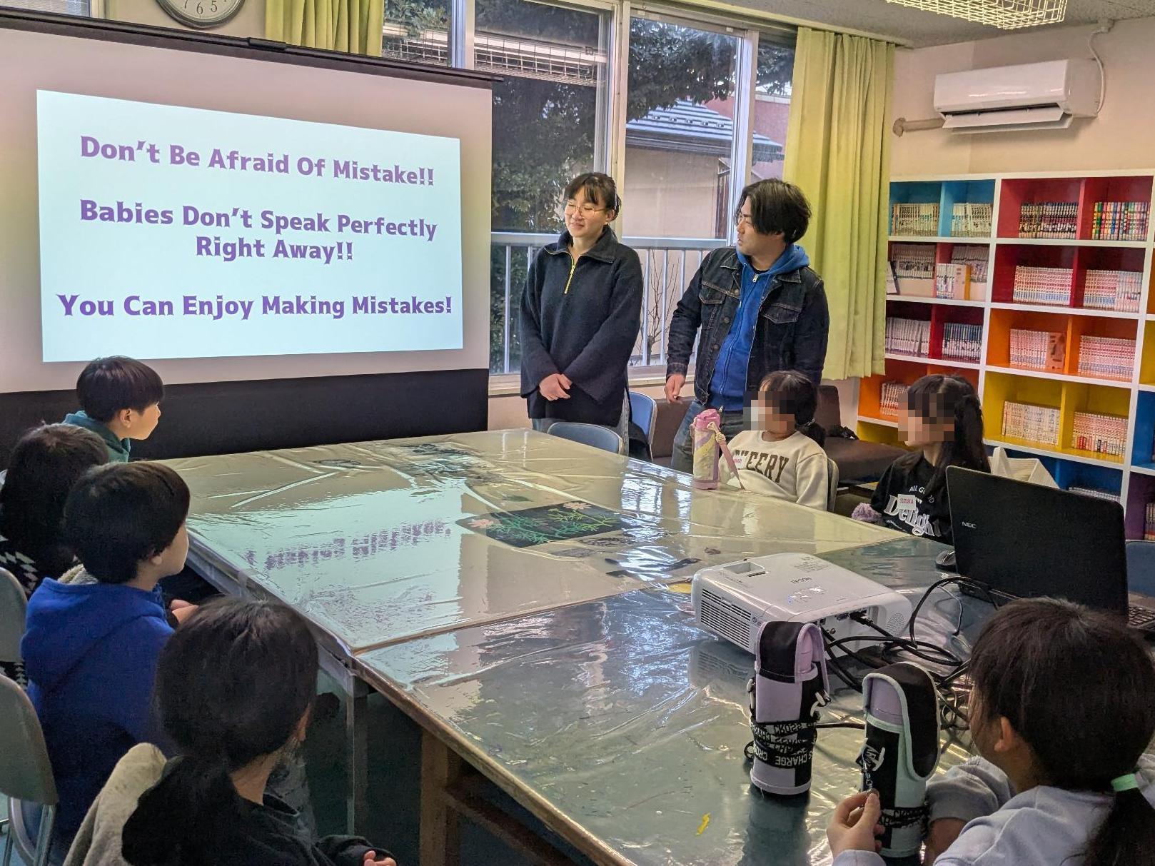 スクリーンに映し出されている英語を小学生7名と先生2名がみている