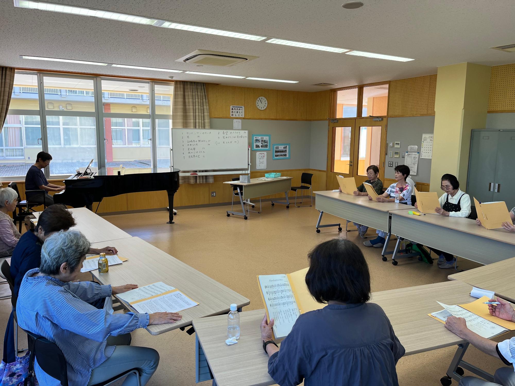 グランドピアノの伴奏で楽譜を見ながら歌っている様子