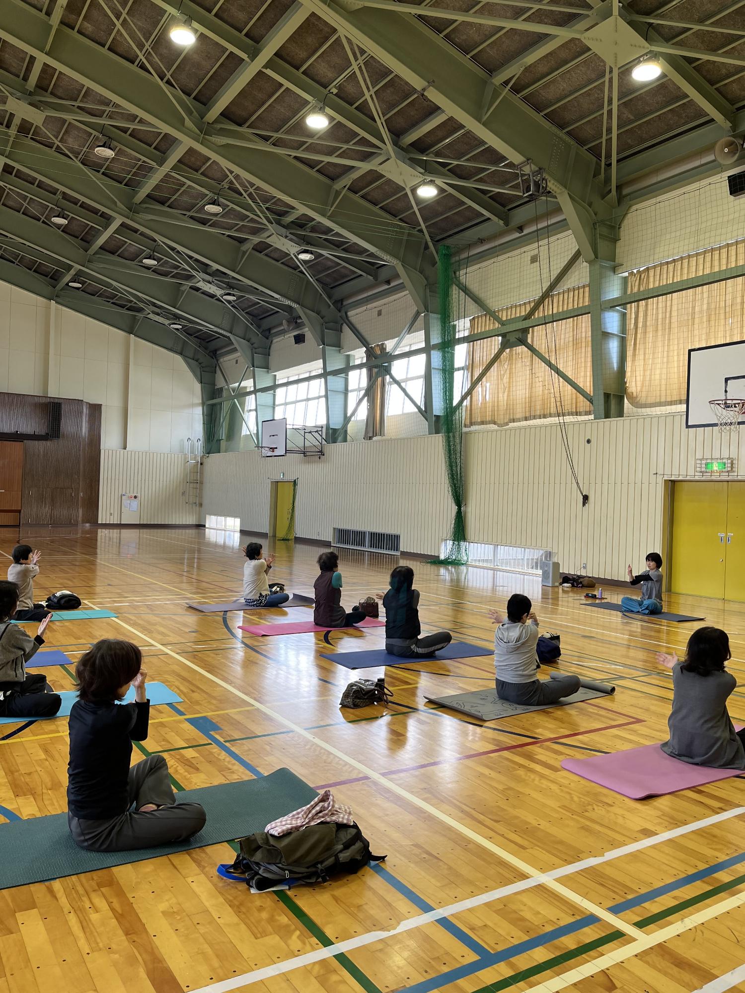 先生のお手本を見ながら、マットの上でヨガをしている様子