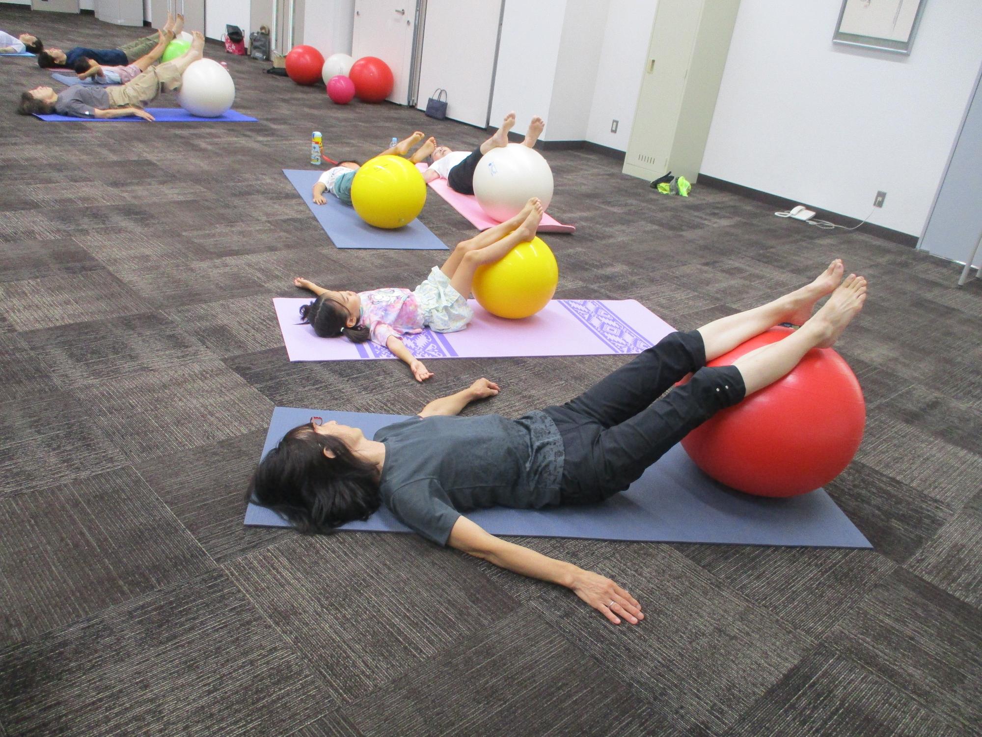 バランスボールに足を載せてリラックスポーズをとる女性と子供