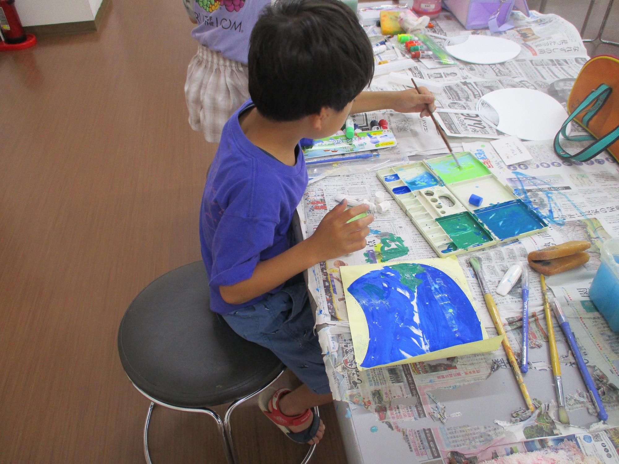 内輪型の用紙に絵を塗っている男の子