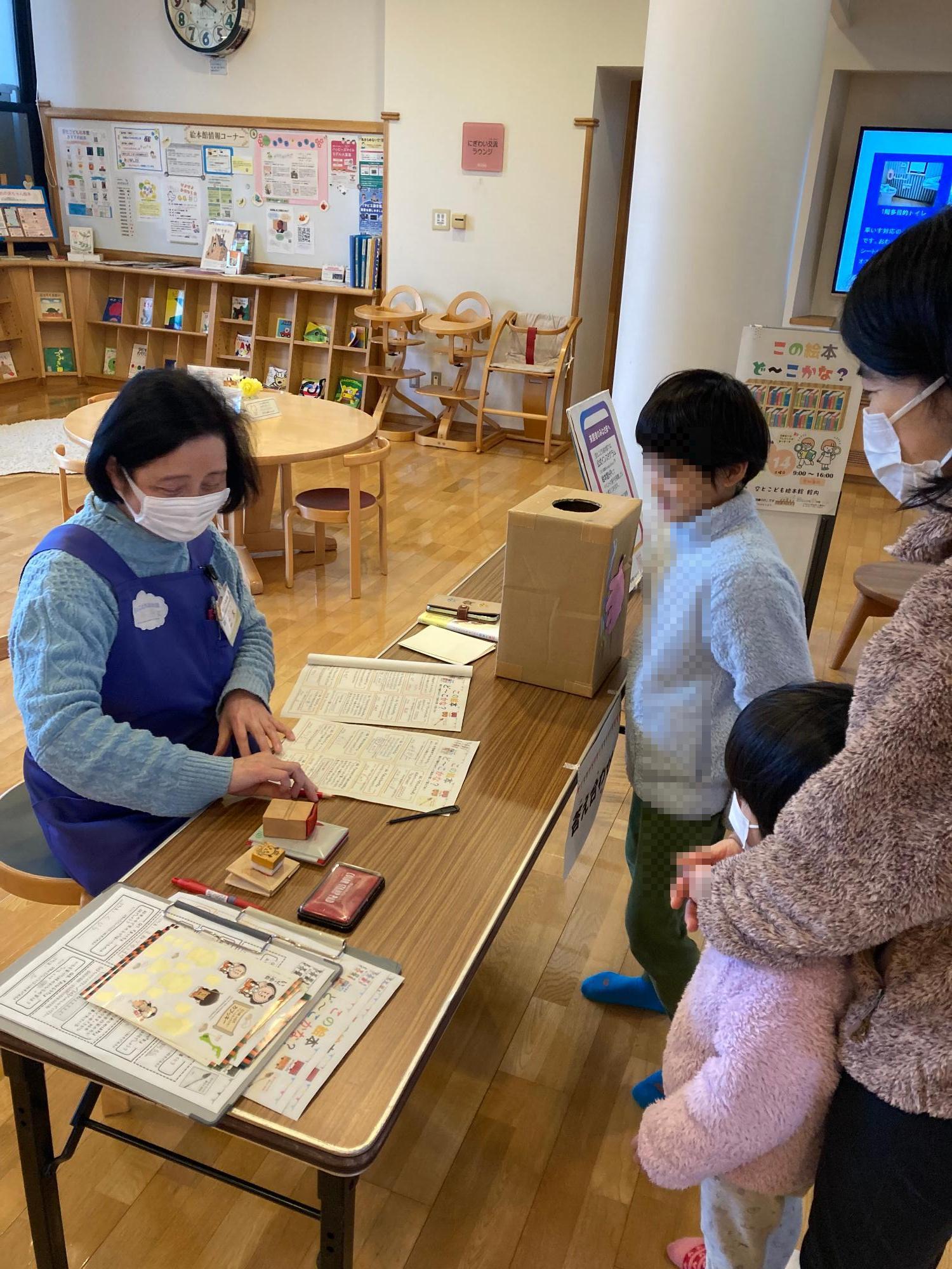 答え合わせをする絵本館館長と親子の画像