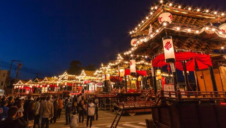 八基曳揃えの写真（夜の街頭にライトアップされた八基の曳山やそれらを観覧する人達がいる）